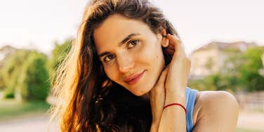 A woman sitting comfortably outdoors with a serene, attentive expression, symbolizing social intelligence, active listening, and conversational ease.