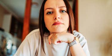 A thoughtful young woman sitting indoors resting her head on her hand, symbolizing emotional self-care, reflection, and strong personal boundaries.