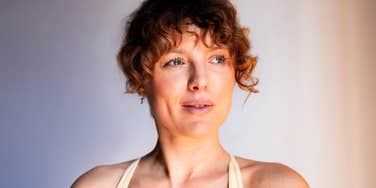 A woman practicing mindfulness meditation indoors with a serene facial expression, symbolizing inner calm, emotional balance, and holistic wellness.