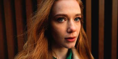 A portrait of a pensive redhead woman looking at the camera, illustrating 'habit-loop processing' and the subconscious drivers behind evening drinking routines.
