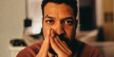 A man looking forward with a somber expression in warm indoor light, symbolizing internal conflict, mental health awareness, and emotional fatigue.