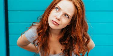 woman who is morally sensitive and self-righteous looking judgmental by a blue wall