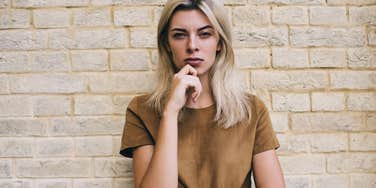 Woman with no respect for authority looking irreverently at camera by a brick wall