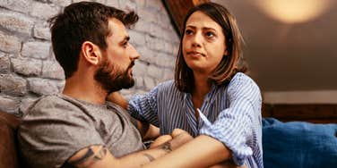 Couple in a relationship that makes them both feel unseen looking sad on a couch 