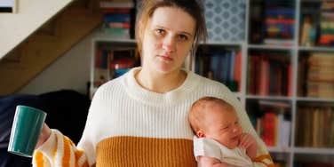 An evocative image of a stressed mother carrying her screaming infant, illustrating the daily mental and financial toll of solo parenting.