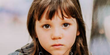 A young girl in a classic collared top staring intently forward, symbolizing youthful intelligence, sharp observation, and family communication dynamics.