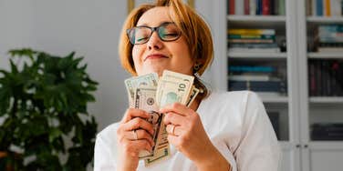 lucky woman holding cash smiling