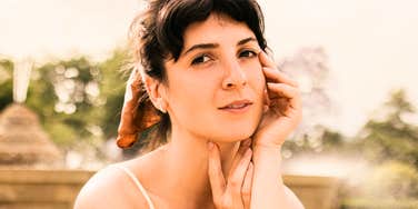 A serene young woman relaxing in natural outdoor sunlight, symbolizing emotional recovery, nervous system regulation, and inner peace.