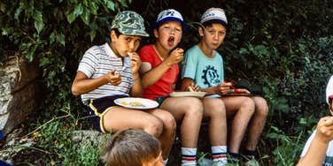 1980s boys eating a snack outside in the woods 