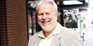 A cheerful, proud Baby Boomer man looking directly at the camera with a confident, bright smile.