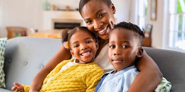 smiling mom hugging her two happy children on the couch