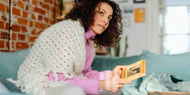 middle aged woman looking at sentimental items at home