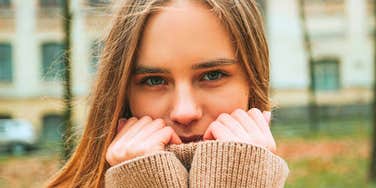 self-aware woman smiling behind her sweater