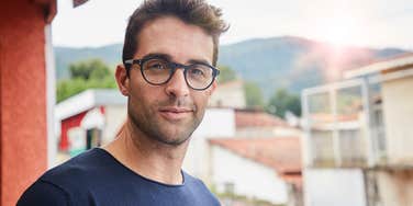 man who'd rather spend money on food and travel looks happy on vacation 