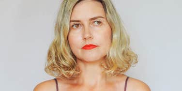 A blonde woman in her 50s standing against a plain white background with a thoughtful, composed expression, symbolizing clean slates, self-reflection, and new beginnings.