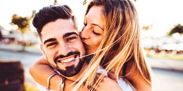 A man giving a woman a piggyback ride on a scenic path at sunset, symbolizing affection, trust, mutual support, and healthy partnership.