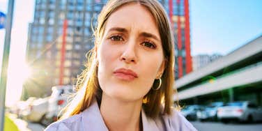 A young woman looking into a web camera with a puzzled, unsure expression, symbolizing communication breakdowns, low emotional intelligence, and interpersonal friction.