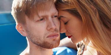 man struggling with physical touch as a woman tries to hug him 