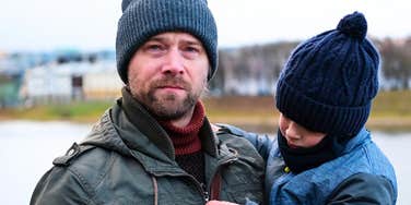 Gen X man holding a child outdoors and looking serious