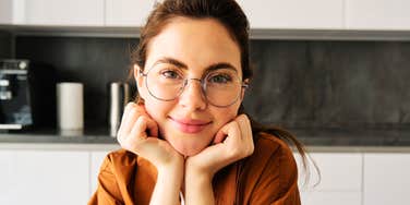 Woman rests her chin on her hands with a calm smile, the easy composure of a natural peacemaker.