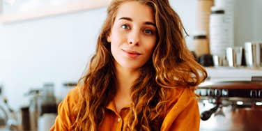 Woman with knowing half-smile and crossed arms, embodying quiet confidence to speak hard truths