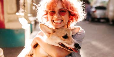 Grinning ear to ear, she hugs her corgi close, the joy of being one dog's favorite person.
