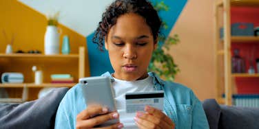 young gen Z woman looking at her credit card and phone