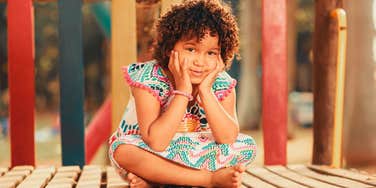 smiling child on the playground sitting 