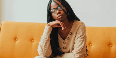 intelligent woman feeling restless sitting on her couch at home