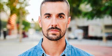 Man who is emotionally weak looking straight into a camera outdoors