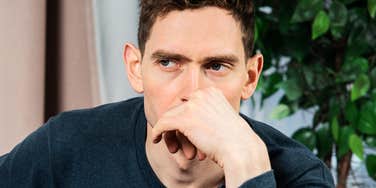 Man's fist pressed near his mouth and guarded gaze reflect the tension anxiety can leave unspoken.