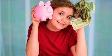little girl holding piggy bank and cash