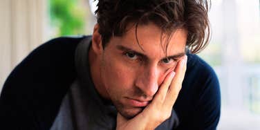 His narrowed, guarded stare peeking over his hand hints at a coldness "nice" doesn't quite cover.