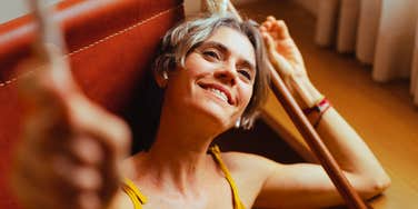 People Who Enjoy Being Around Fewer People As They Get Older Often Have Things In Common Woman lounges alone at home with a contented smile, at ease in her own company.