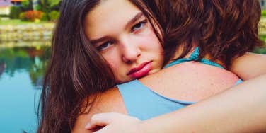 A warm hug, but her flat, watchful stare hints at something colder underneath the surface.