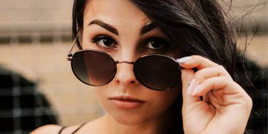 She peers over her sunglasses with a knowing look, the quiet awareness of catching a lie.