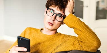 Man who is self-important attitude looking over his phone dryly