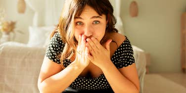 Woman covers her mouth, wide-eyed, the instant realization a casual comment may have landed wrong.