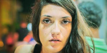 Woman's tired, distant gaze reflects the quiet weight of a childhood that felt normal at the time.