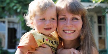 Mom who was raised with little but has lots of love cuddles her own toddler