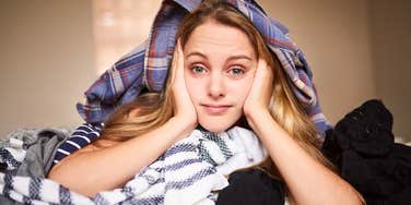 Woman under her messy laundry in her house 