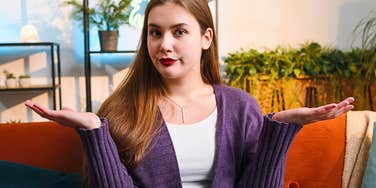 Woman roommate who is annoying shrugs on a couch 