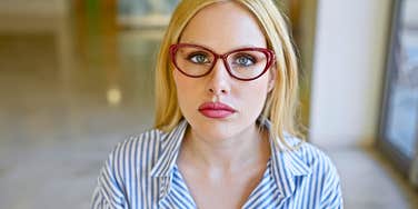woman wearing glasses feeling everything looks directly at camera