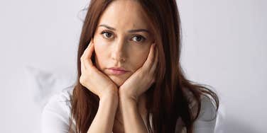 woman who hasn't been happy in a while rests chin in her hands