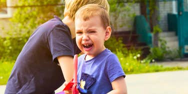 child crying while mom sitting behind him ignores it