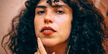 Phrases People Say When They Think They're Smarter Than Everyone Else arrogant woman touching her chin feeling superior