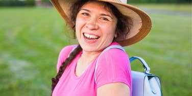 Woman in a sun hat laughs in a field, the wholesome imagery at the center of the tradwife debate.