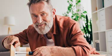 retired man fixing something for a family member 