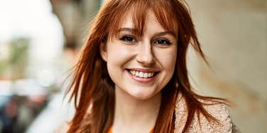 Woman who feels powerful smiles warmly outdoors 