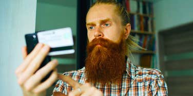 frugal man looking at his credit card not wanting to spend money